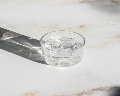 A clean glass of clear water with ice and a slice of lemon